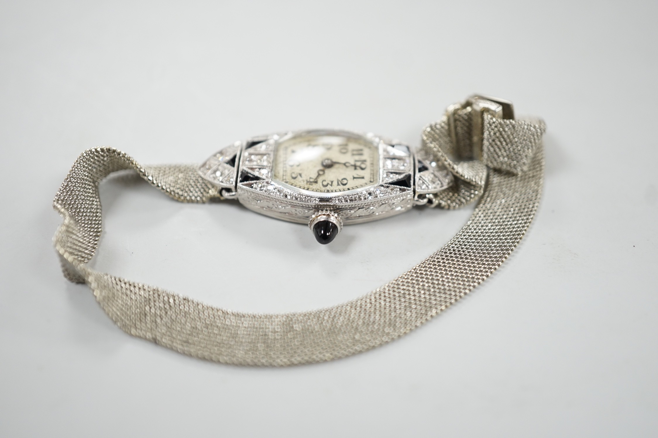 An Art Deco white metal (stamped platine) black onyx and diamond cluster set cocktail watch, on a 750 white mesh bracelet, approx. 16cm, gross weight 18.7 grams.